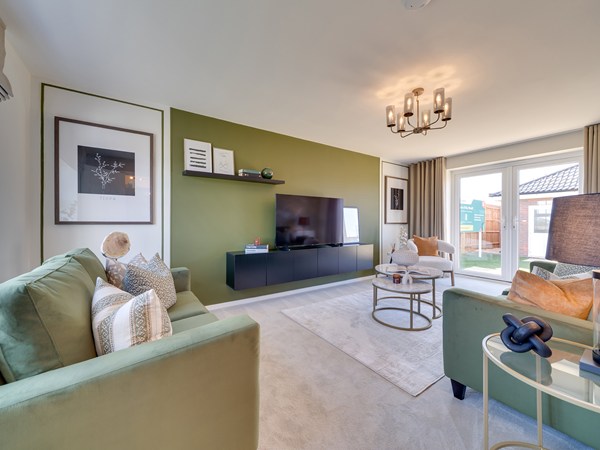 Living room with two green velvet sofas and matching green walls. a TV is shown in the middle. there are French doors opening onto the garden