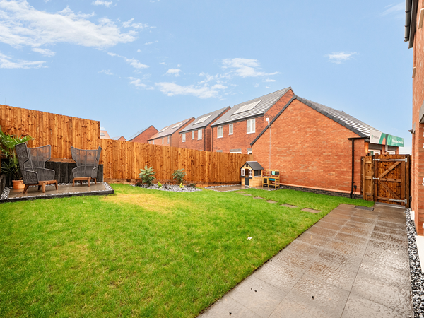 Enclosed rear garden with patio area and neat lawn behind a new build home.