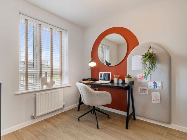 A beautiful and spacious modern office room with an orange feature wall and a small desk. 