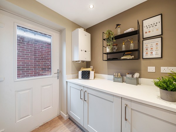 Modern utility room with fitted storage, worktop and external door.