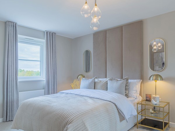 Elegant double bedroom with a feature headboard, soft neutral décor, bedside tables and a large window.