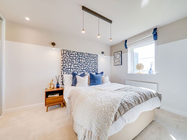 Double bedroom in The Burnham at Bluebell Meadow with striped walls and fitted décor.