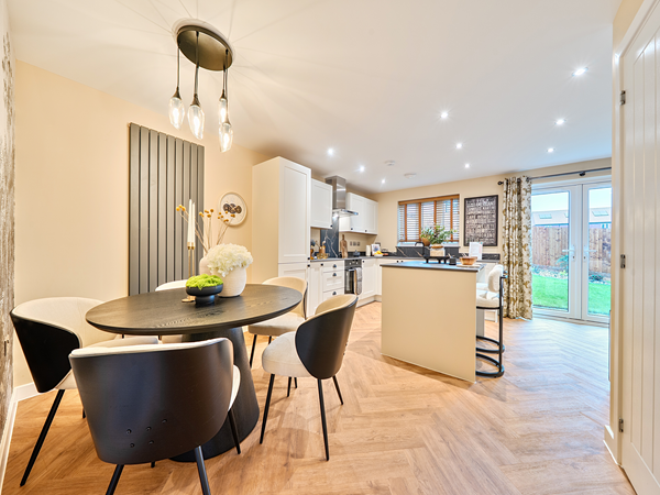 Open-plan kitchen and dining area with round table and modern lighting.