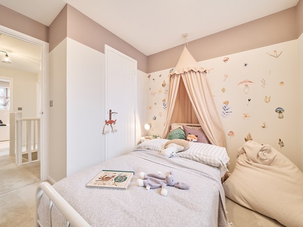 Childrens-bedroom-with-soft-pink-canopy-bed-woodland-wall-with-cosy-beanbag-and-plush-toys