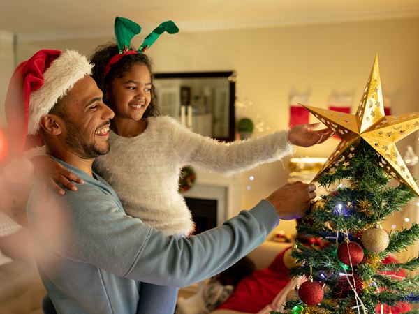 Dad Holding Child Putting Star on Christmas Tree