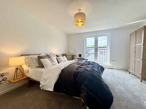 Main bedroom in the Wykeham new build home with balcony doors and neutral décor.