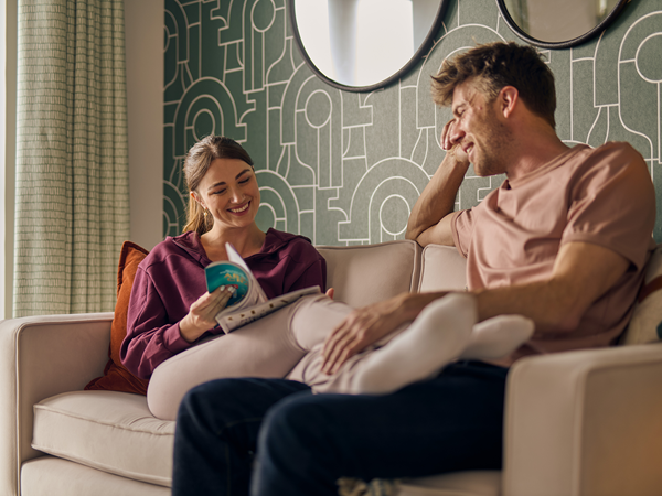 A young couple sitting on a sofa flicking through a magazine