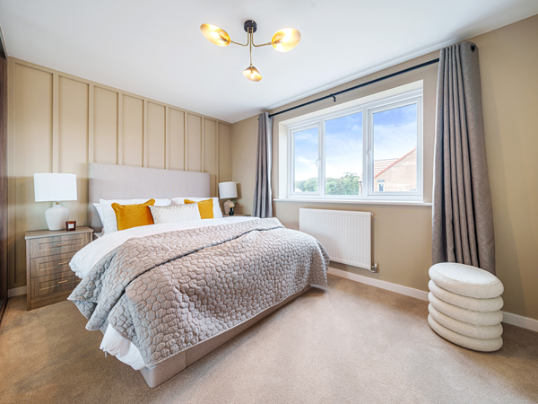 Spacious bedroom with double bed, feature wall and large window.