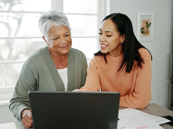 A mother and daughter looking at a laptop together and talking.