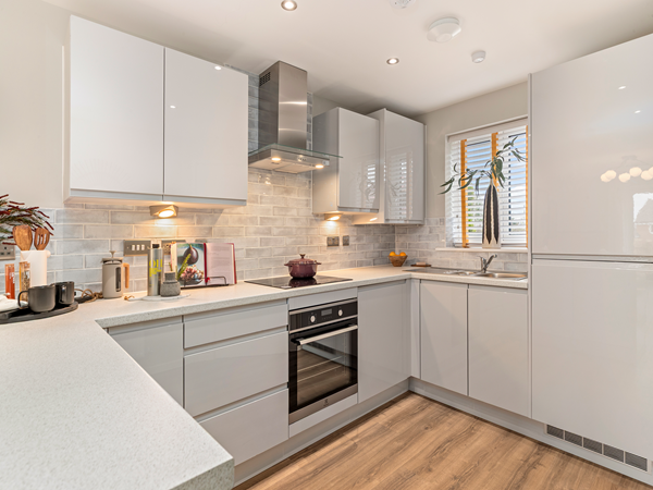Kitchen with oven, glossy cabinets and tiled splashback.
