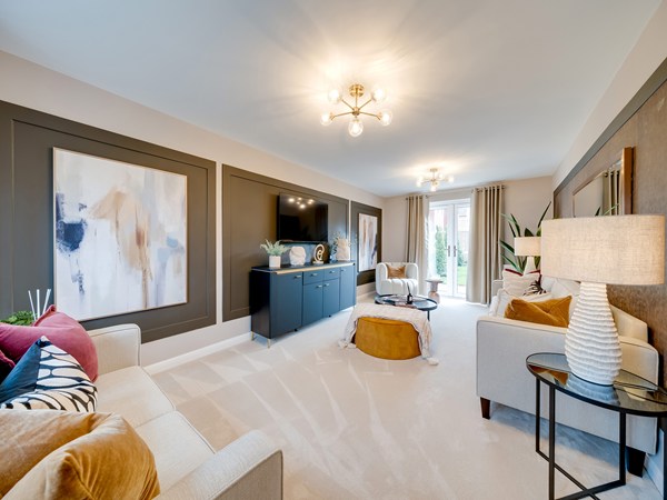 Bright living room with two sofas, a TV mounted on a dark feature wall, abstract artwork, and large glass doors opening to a garden