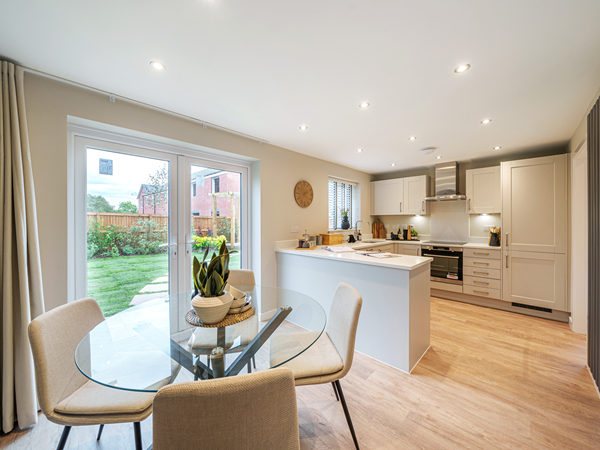 Open-plan kitchen and dining area with breakfast bar and garden doors.