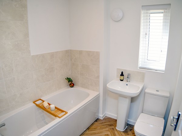 Bathroom with bath, pedestal sink and toilet in the Greenwood at Trehenlis Gardens.