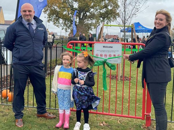 Two Persimmon staff members opening a play area at a Persimmon development. 