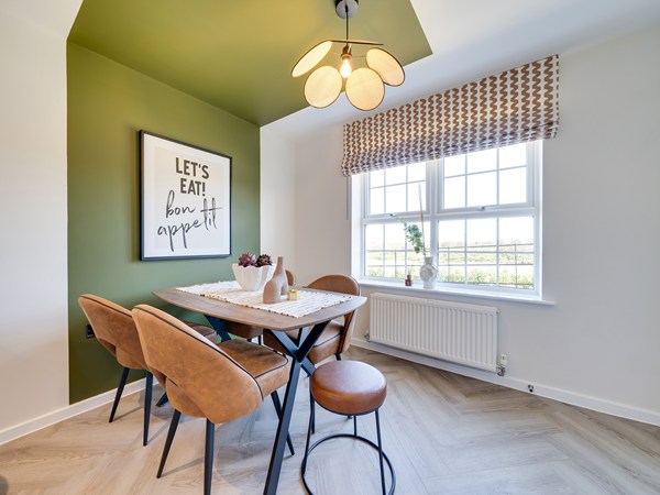 Dining area showing small dining table in wood and black, with 4 brown leather chairs and a matching stool. A double window is behind the table.