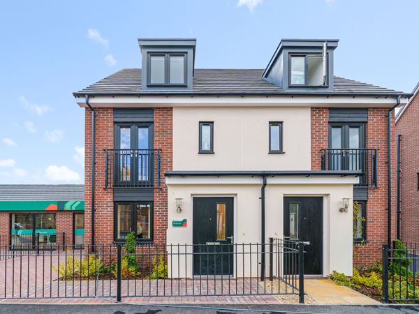 The exterior of a modern three-storey Persimmon home against a blue sky.