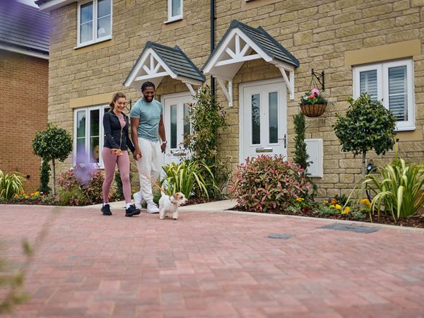 A couple walking their dog outside of a new build Persimmon home.