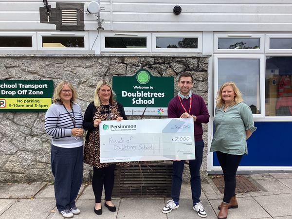 Persimmon Homes representatives present a £2,000 donation cheque to Doubletrees School staff outside the school entrance.
