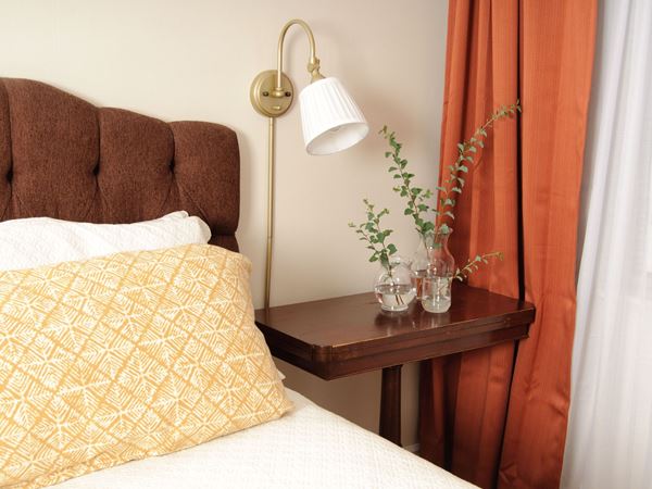 A beautiful bedroom with brown furniture and a bright orange curtain.