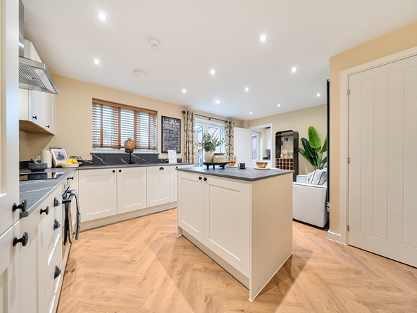 Spacious open-plan kitchen with island unit, white cabinets and herringbone flooring.