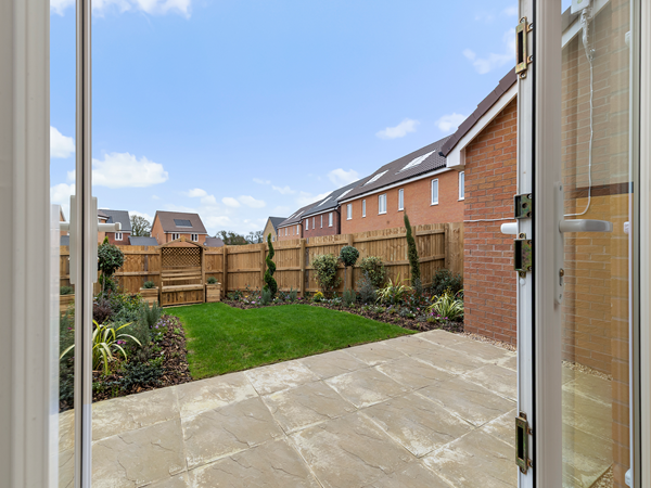 Garden view from patio doors showing lawn, fence and planting.