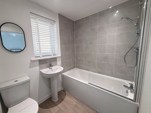 Modern bathroom with bath and grey tiling at Trevithick Manor Park home.