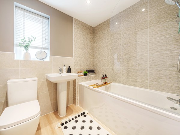 Modern bathroom with bath, shower, pedestal sink and neutral tiles.