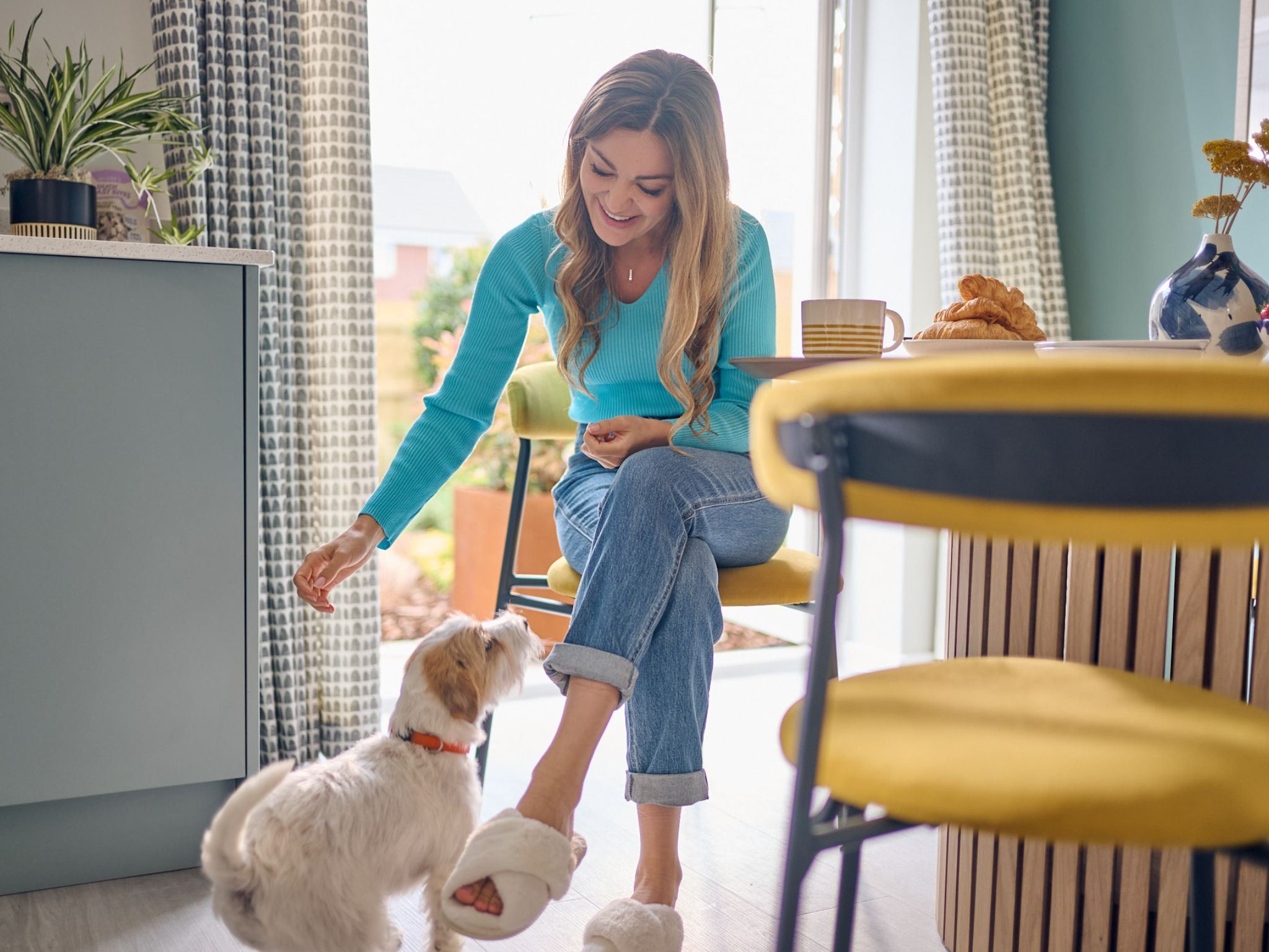 A young woman playing with a dog in a Persimmon homes dining room, 