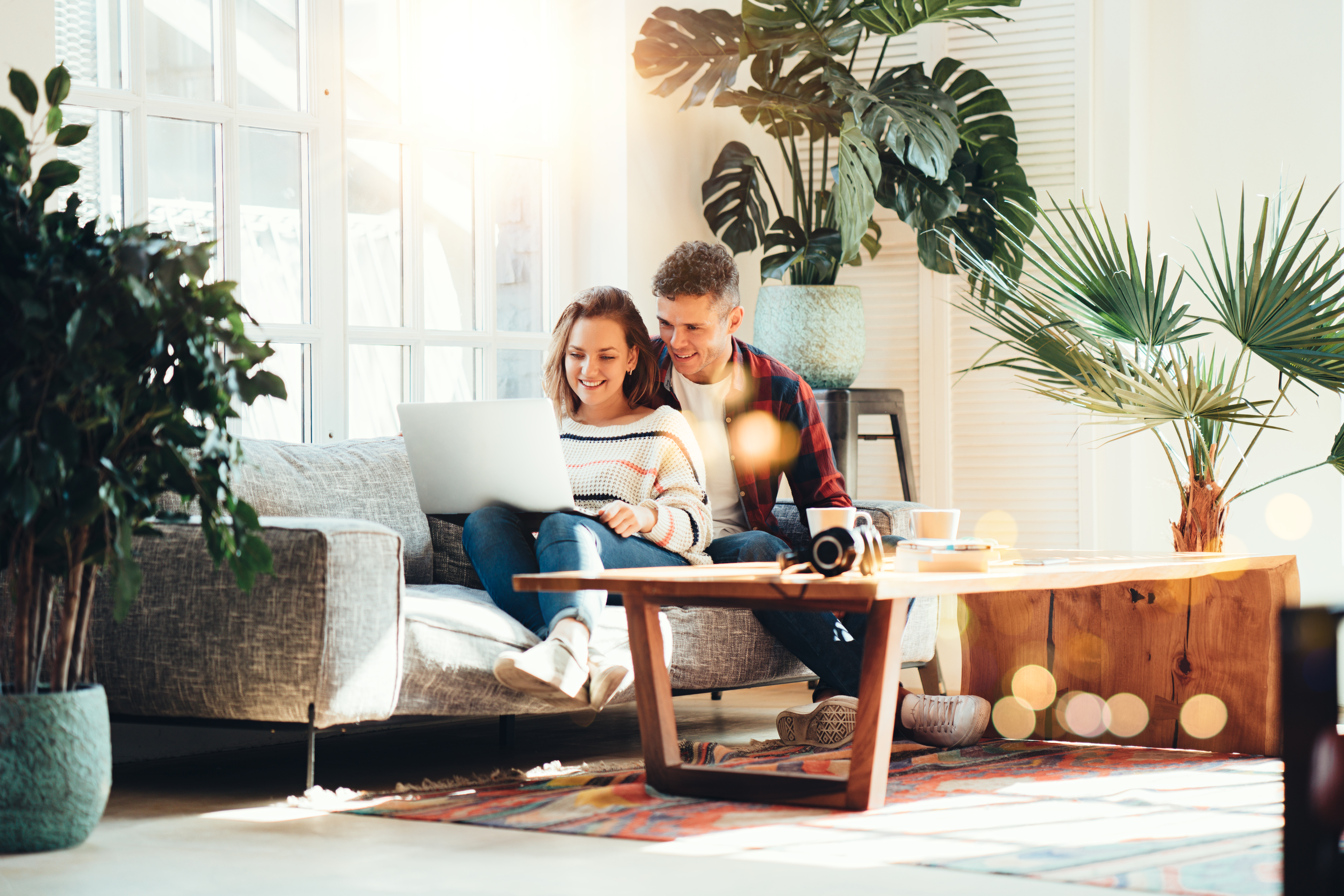 Couple on Couch with Laptop Surrounded by Plants