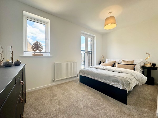 Double bedroom in the Wykeham new build home with neutral styling and balcony doors.