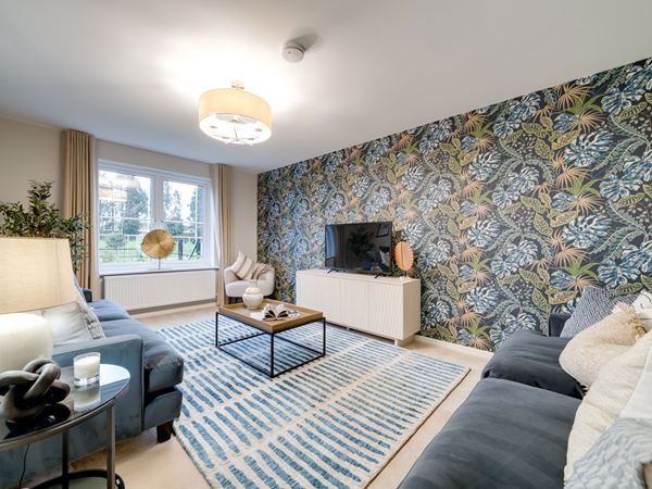 Living room in the Kielder show home at Hawthorn Park with blue sofas, patterned feature wall and TV.