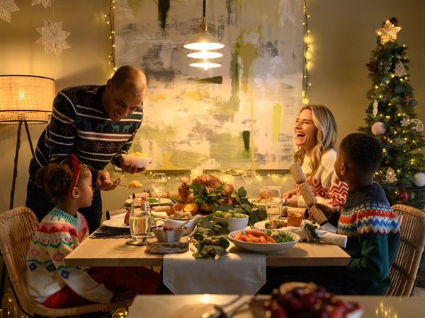 A mother, father, and their two kids enjoying Christmas dinner on Christmas day in a modern dining room. 