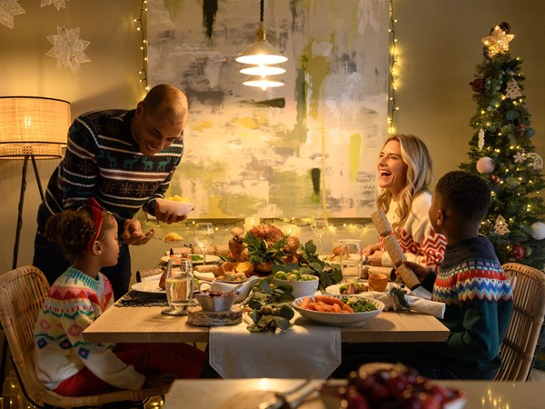 A mother, father, and their two kids enjoying Christmas dinner on Christmas day in a modern dining room. 