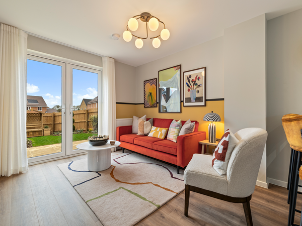Living area with bright sofa, artwork and large doors opening to garden. 
