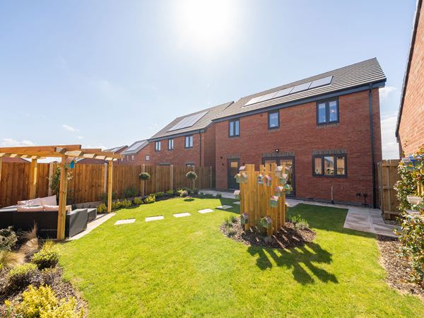 Rear garden view of The Burnham at Bluebell Meadow with lawn and patio.