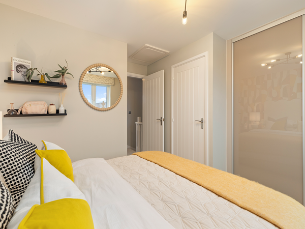 Bedroom view showing shelving, mirror and built‑in wardrobe.