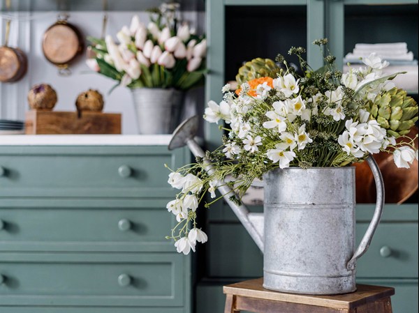 watering can as a vase with white flowers and green kitchen
