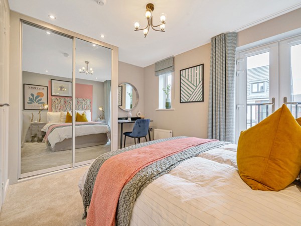 Bedroom with mirrored fitted wardrobes, dressing area, French doors and neutral décor.
