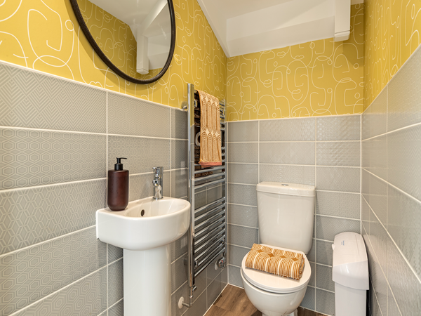 WC with pedestal sink, toilet and yellow patterned wallpaper.c