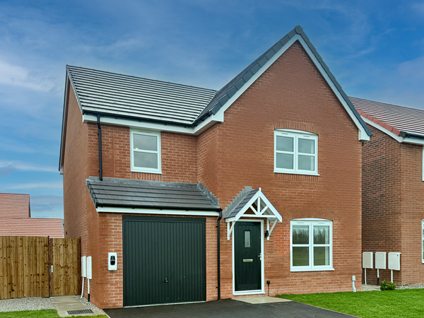Modern red-brick detached house with white windows, dark garage door, and pitched roof.
