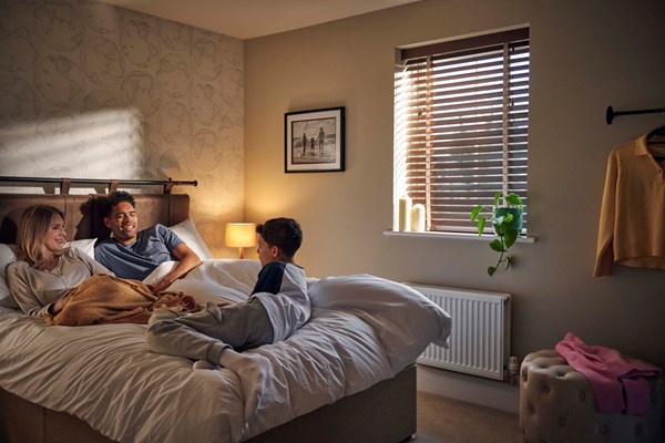 A mother, father, and son enjoying a modern bedroom in a premium new home by Charles Church