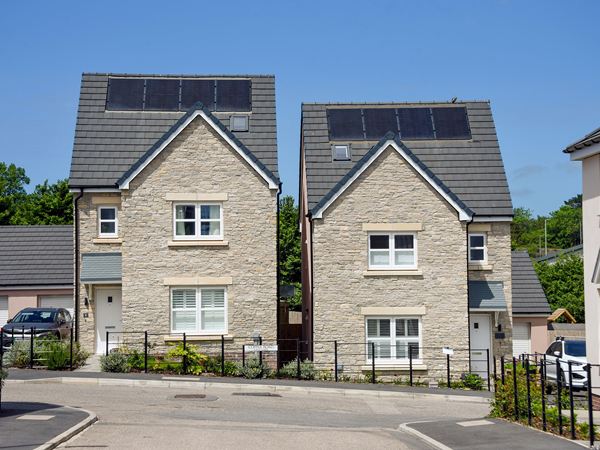Street view of stone-fronted new build homes with solar panels at Trehenlis Gardens.
