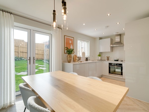 Modern kitchen/dining room with gloss units, dining table, pendant lighting and French doors to the garden.