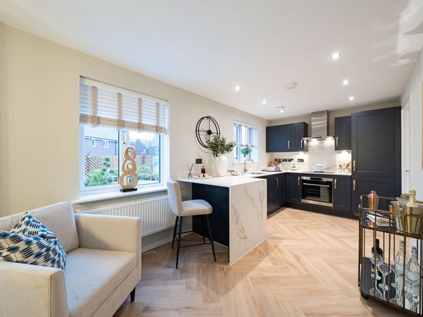 Kitchen in the Kielder show home at Hawthorn Park with dark cabinets, breakfast bar and wood-effect flooring.