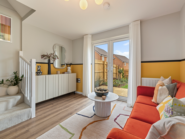 Living space with sofa, feature rug and staircase beside French doors.