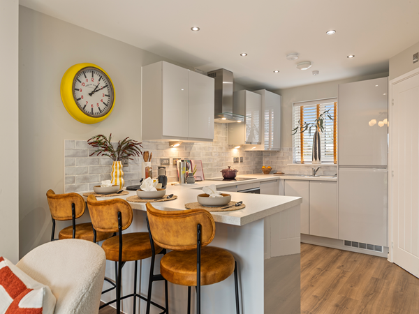 Modern kitchen with breakfast bar, leather bar stools and glossy cabinets.