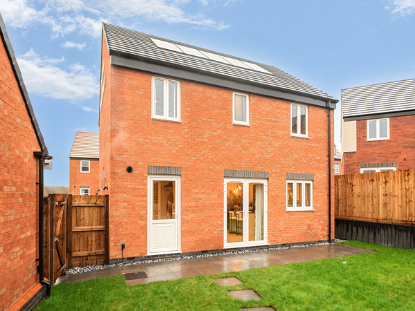 Rear view of a red-brick new build home with French doors and garden.