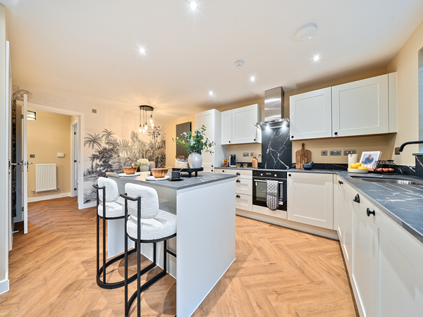 Modern kitchen with breakfast bar, white cabinets and warm wood flooring.