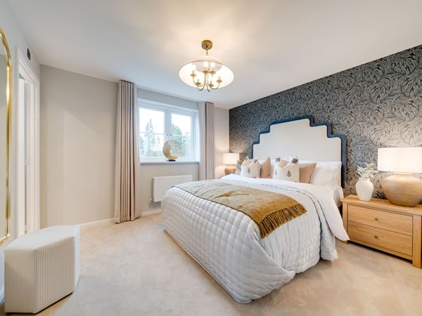 Bedroom in the Kielder show home at Hawthorn Park with blue walls, double bed and wooden chest of drawers.