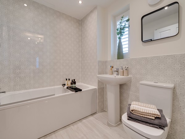 main bathroom with bath, sink and toilet. a Neutral printed tile and white walls